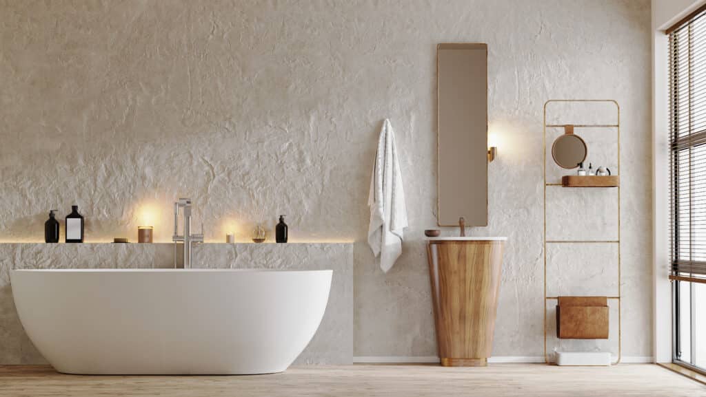 Salle de bain moderne aux murs texturés beige. Baignoire îlot blanche, meuble lavabo bois, étagère dorée. Ambiance chaleureuse avec lumières.